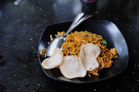 Fried noodle with pork and dumpling on black plate