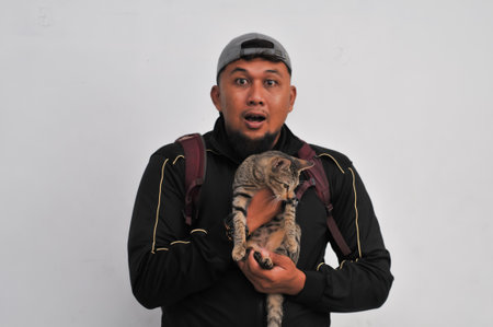 Asian man holding a cat and looking at camera on white background.