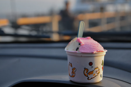 Ice cream in a cup on the roof of a car. Selective focus.