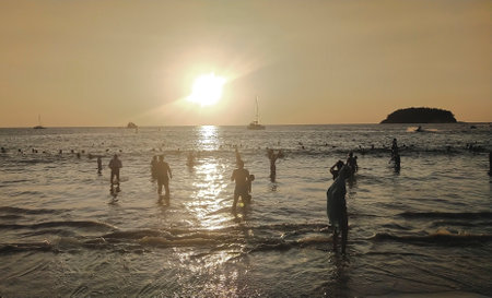 Unidentified people bathe in the sea at sunset.の写真素材