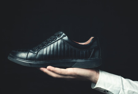 Hand holding black shoe.の写真素材