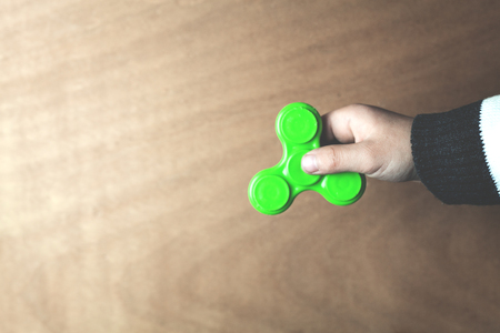Hand showing spinner on a wood background.の写真素材