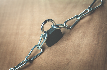 Padlock and chains on a wood background.の写真素材