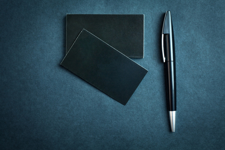 Black business cards and pen on a blue background.の写真素材