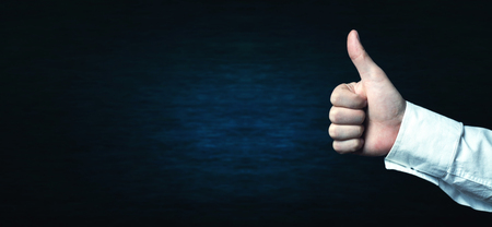 Hand showing thumb up on a blue background.の写真素材