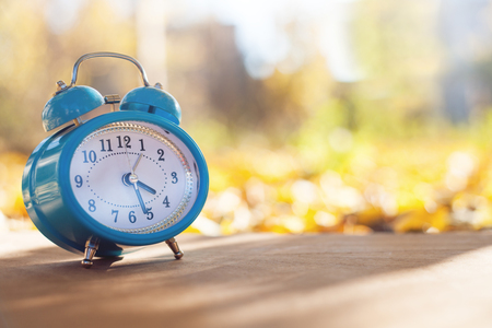 Alarm clock on a autumn background.の写真素材