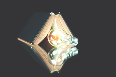 Light bulb with book on a black background.の写真素材