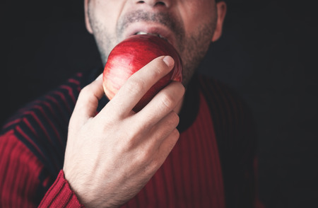 Caucasian man eating red apple.の写真素材