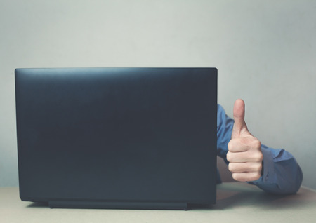 Man using computer and showing thumb up sign.の写真素材