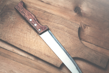 Cutting board and knife on a wood background.の写真素材