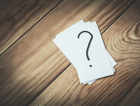 Question mark in paper on a wood background.の写真素材