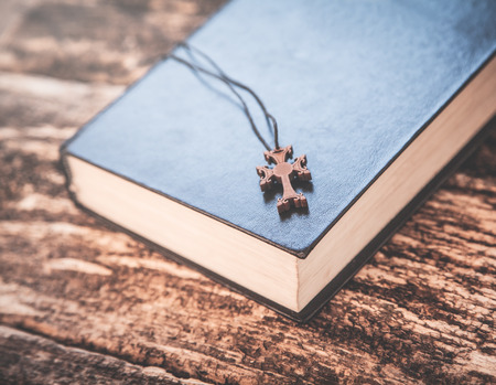 Bible and cross on a wood background.
