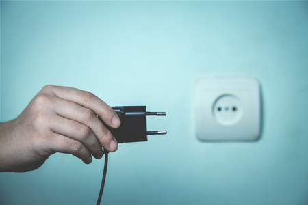 Hand shows charger into wall socket.の写真素材