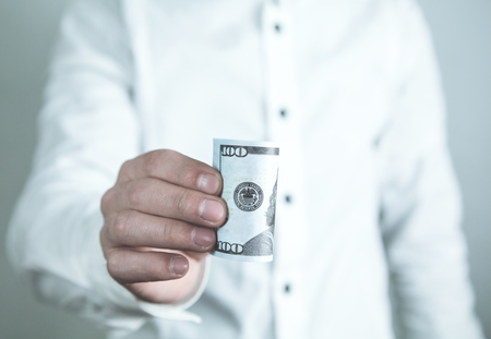 Caucasian businessman holding roll of hundred dollar.の写真素材