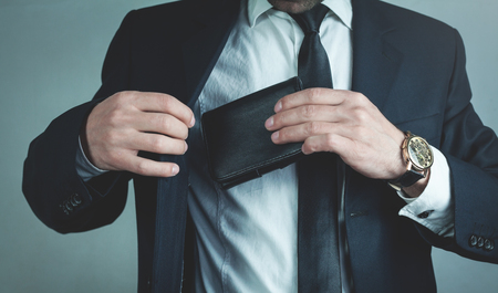 Businessman pulls his leather wallet into suit pocket.の写真素材