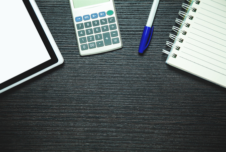 Digital tablet, calculator, pen and notepad on dark wood background.  Business conceptの写真素材