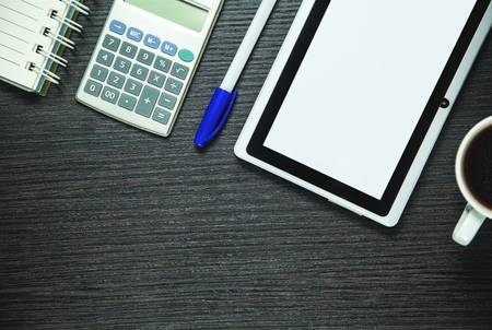 Digital tablet, calculator, pen, coffee and notepad on dark wood background.  Business conceptの写真素材