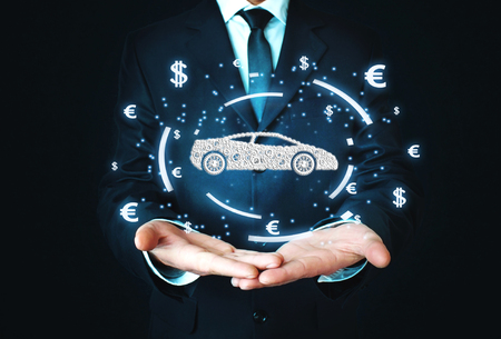 Businessman holding car and currency symbols. Concept of buy carの写真素材