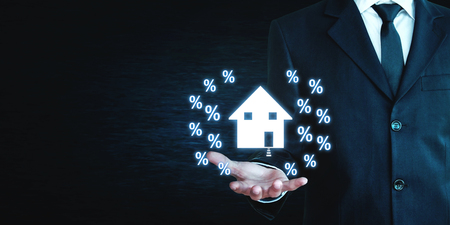 Man holding house and percent signs.の写真素材