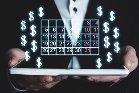 Man holding calendar and dollar signs.の写真素材