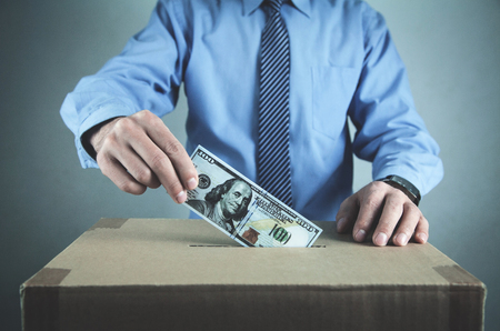 Man putting money on cardboard box. Save moneyの写真素材