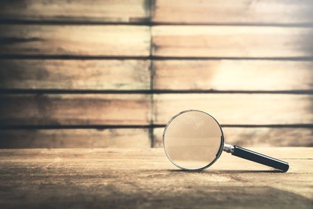Magnifying glass on wooden table. Search and discoverの写真素材