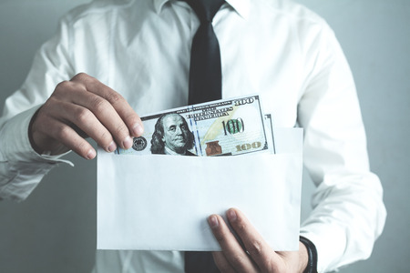 Caucasian businessman putting hundred dollars in envelope.の写真素材