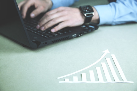Paper growth graph on desk. Man using laptopの写真素材