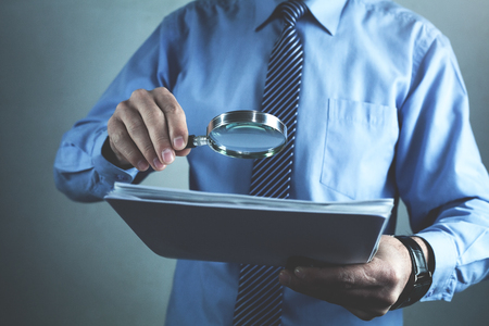 Businessman with magnifying glass reading documents.の写真素材