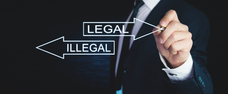 Man writing Illegal and Legal words with arrows on screen.の写真素材