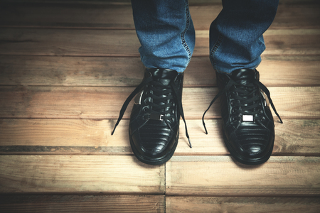 Fashion Man in black sneaker with blue jeans on the wooden floor background.の写真素材