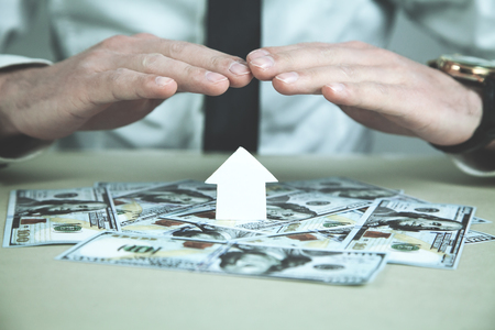 Man protect paper house with a dollars. House insuranceの写真素材