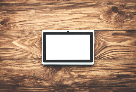 White digital tablet on a wooden desk.の写真素材