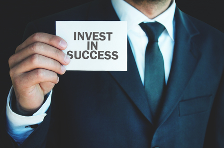 Businessman showing Invest In Success word on business card.の写真素材