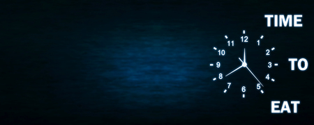 Clock with Time To Eat words on a dark blue background. Time To Eat Conceptの写真素材