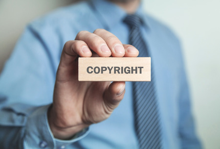 Businessman showing Copyright word in wooden block. Business conceptの写真素材