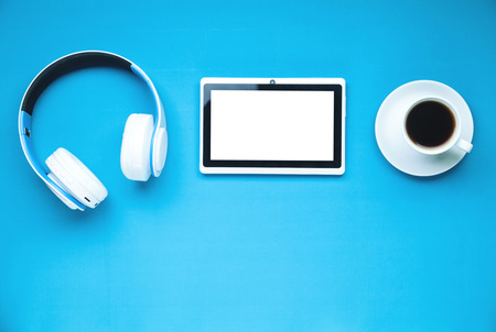 Headphones, tablet and coffee cup on a blue background.の写真素材