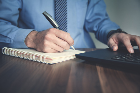 Businessman writing in notepad and using computer. Business conceptの写真素材