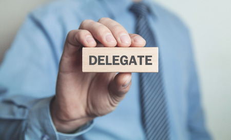 Businessman showing Delegate word in wooden block. Business conceptの写真素材