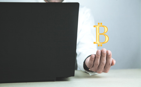 Businessman using laptop and holding Bitcoin symbol.の写真素材