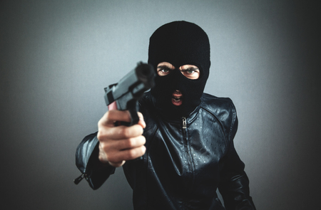 Aggressive man in a black mask with a pistol.の写真素材