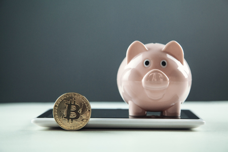 Golden Bitcoin with piggy bank on a digital tablet. Cryptocurrency investment conceptの写真素材
