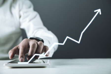 Man touching white arrow on a digital tablet screen. Success conceptの写真素材