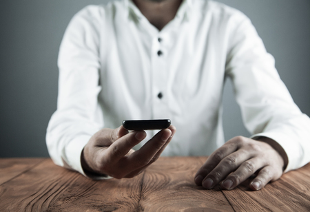 Man holding smartphone in his desk. Business conceptの写真素材