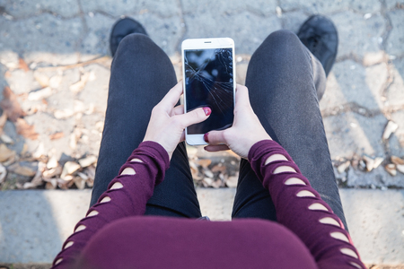 Woman holding broken smartphone in outdoor.の写真素材