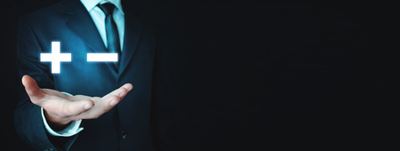 Man holding plus and minus signs. Business conceptの写真素材