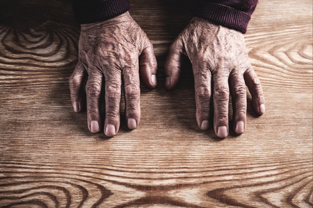 Old woman hands on wooden table.の写真素材