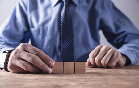 Businessman holding wooden cube on a wooden table.の写真素材