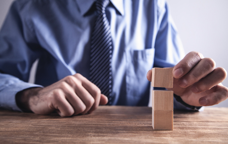 Businessman holding wooden cube on a wooden table.の写真素材