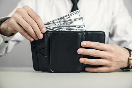 Caucasian businessman putting money into wallet.の写真素材